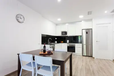 a kitchen with white cabinets and a table and chairs at 2512 - AB Comte dUrgell P-II in Barcelona