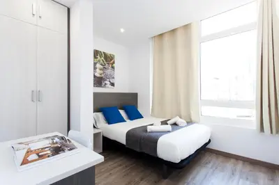 a bedroom with a bed with blue pillows and a window at 2513 - AB Comte dUrgell II-I in Barcelona