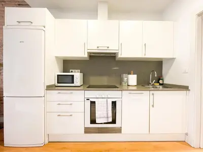 a kitchen with white cabinets and a white refrigerator at Boutique Pare Lainez in Barcelona