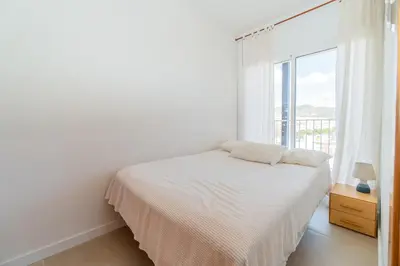 a white bedroom with a bed and a window at Horizonte Azul Sitges in Sitges