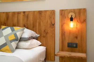 a bedroom with a wooden headboard and a light on the wall at Jardinets Guest House in Barcelona