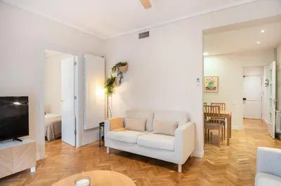 a living room with a white chair and a television at Warmth and comfort in the sought-after Eixample in Barcelona
