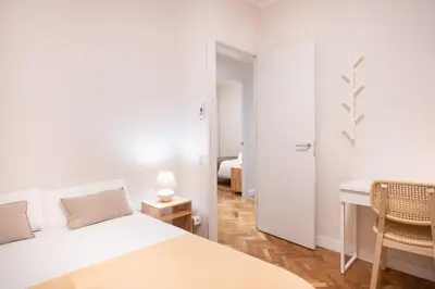 a white bedroom with a bed and a desk at Warmth and comfort in the sought-after Eixample in Barcelona