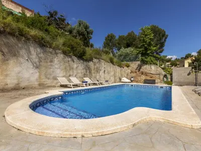 a swimming pool with chairs and a rock wall at Holiday Home Villa Rosales by Interhome in Gornal