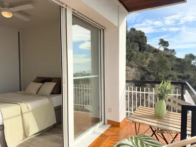 a bedroom with a bed and a balcony with a view at Atico Isabel in Castelldefels