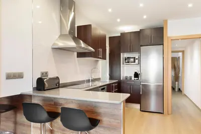 a kitchen with a counter with chairs and a refrigerator at El balcón de Sagrada Familia in Barcelona