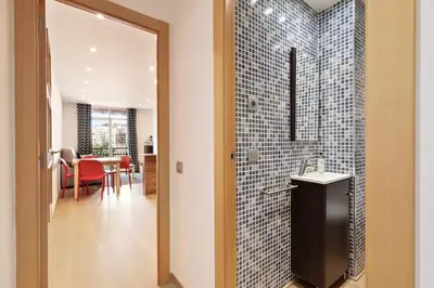 a bathroom with a walk in shower next to a dining room at El balcón de Sagrada Familia in Barcelona