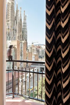 a bird sitting on a balcony looking out at a city at El balcón de Sagrada Familia in Barcelona