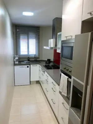 a large kitchen with white cabinets and a tv at The White Lilies in Pineda de Mar