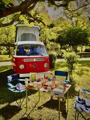 a table with chairs and a van parked in a yard at Retro VW Kombi T2 Campervan in Hospitalet de Llobregat