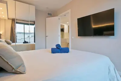 a bedroom with a large bed with a television on the wall at YOUR HOME- Apartment Camp Nou 2a in Hospitalet de Llobregat