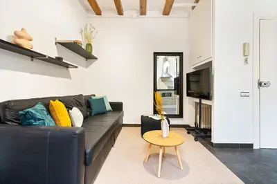 a living room with a black couch and a table at Lodging Apartments Almirall Beach 22 in Barcelona