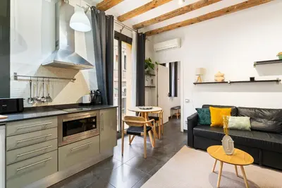 a kitchen and living room with a couch and a table at Lodging Apartments Almirall Beach 22 in Barcelona