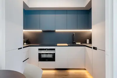 a kitchen with white cabinets and blue walls at Hauzify I Apartaments Voramar in San Pol de Mar