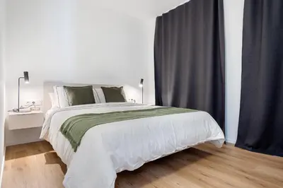 a bedroom with a large white bed with green pillows at Hauzify I Apartaments Voramar in San Pol de Mar