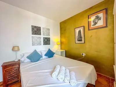 a bedroom with a large white bed with blue pillows at Sira House by Hello Homes Sitges in Sitges