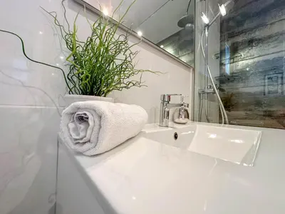 a bathroom with a white sink and a plant at Sira House by Hello Homes Sitges in Sitges