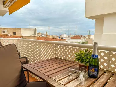 a bottle of beer sitting on a wooden table on a balcony at Sira House by Hello Homes Sitges in Sitges