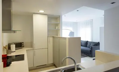 a kitchen with a sink and a living room at Durlet Rambla Mar Apartments in Barcelona