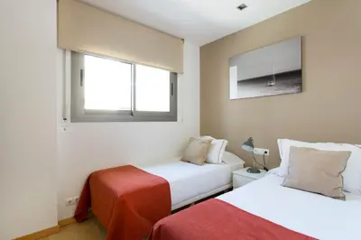 two beds in a room with two windows at Durlet Rambla Mar Apartments in Barcelona