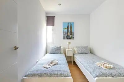 two beds in a room with white walls at Ma Bright apartment next to Parc de Montjuïc in Barcelona