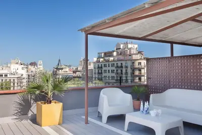 a balcony with a couch and chairs on a roof at Enjoybcn Miro Apartments in Barcelona