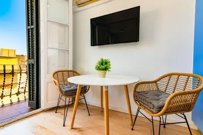 a table and two chairs with a tv on a balcony at R&B Mila in Barcelona