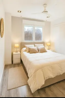 a white bedroom with a large bed with two lamps at Apartamento Sol Terraza in Montgat