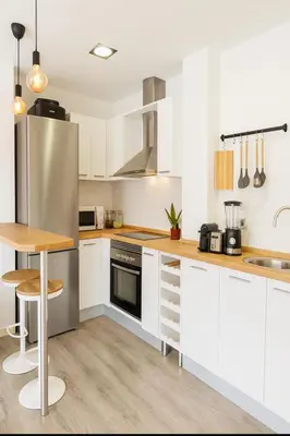 a kitchen with white cabinets and a stainless steel refrigerator at Apartamento Sol Terraza in Montgat