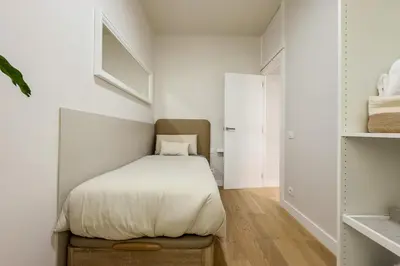 a small bedroom with a bed with white sheets at Barcelona Amelie Apartment in Hospitalet de Llobregat