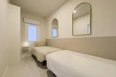 a white lamp on a night stand next to a bed at Barcelona Aura Apartments in Hospitalet de Llobregat