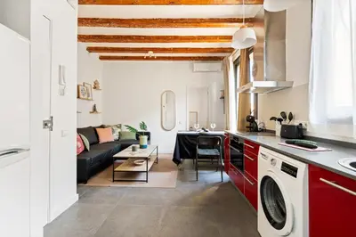 a kitchen and living room with red cabinets and a couch at Lodging Apartments Almirall Beach 51 in Barcelona