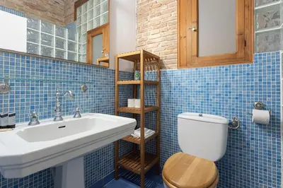 a blue tiled bathroom with a sink and a toilet at Canela Homes BARCELONA JOVELLANOS in Barcelona