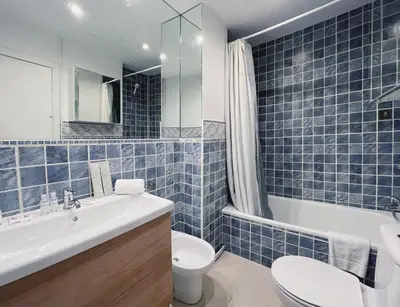 a blue tiled bathroom with a toilet and a sink at Stay U-nique Apartment General Mitre in Barcelona