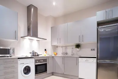 a kitchen with white cabinets and a washer and dryer at Feelathome Mozart Apartments in Barcelona