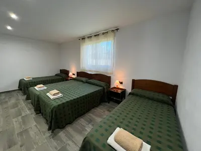 a room with two green beds and a window at VILLA MasÍa CAL TONI in Pineda de Mar