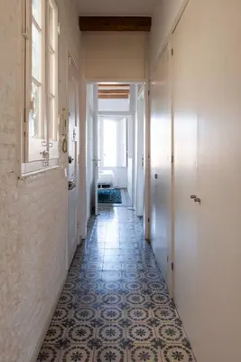 a hallway with a tile floor and white walls and a window at Enchanting 2 BR flat with terrace near Plaça Espanya in Barcelona