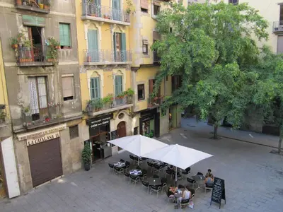 a group of people sitting at an outdoor table with umbrellas at Olles Apartment in Barcelona