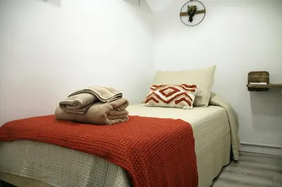 a bedroom with a bed with a red blanket and a clock at Apartamento Lauda in Hospitalet de Llobregat