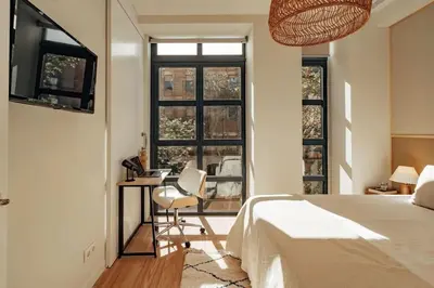 a bedroom with a bed and a desk and windows at Casa Macaya - 1b apartment in Eixample in Barcelona