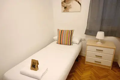 a small bedroom with a white bed and a nightstand at Homenfun Barcelona Eixample ll in Barcelona