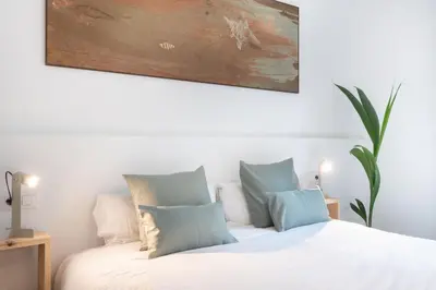 two white beds in a room with a painting on the wall at Charming renovated Apt minutes from the center in Barcelona
