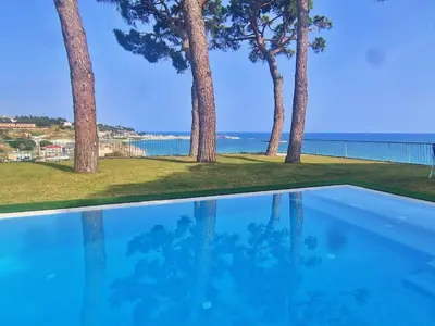 a pool with trees and the ocean in the background at Preciosa casa al borde de un acantilado in Arenys de Mar