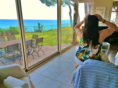 a woman sitting on a bed looking out at the ocean at Preciosa casa al borde de un acantilado in Arenys de Mar
