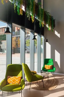 two green chairs and a table in a room with windows at Atenea Living in Mataró