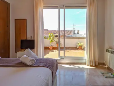 a bedroom with a bed and a view of a balcony at Castell Apartment by Hello Homes Sitges in Sitges