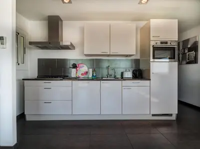 a white kitchen with white cabinets and appliances at Atalaya Apartment by Hello Homes Sitges in Sitges