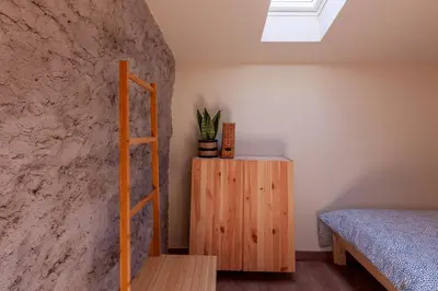a bedroom with a bed and a ladder next to a wall at Cal Simon- Casa a Montserrat in Collbató