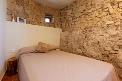 a bedroom with a bed in a stone wall at Cal Simon- Casa a Montserrat in Collbató