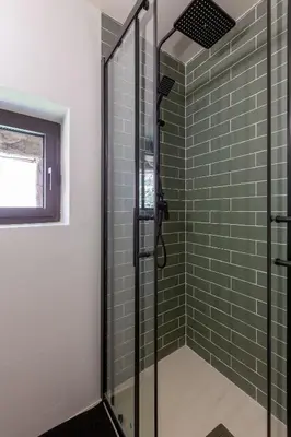 a bathroom with a shower with green subway tiles at Cal Simon- Casa a Montserrat in Collbató